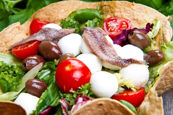 Смешанный салат с моцареллой и анчоусами в корзине — стоковое фото