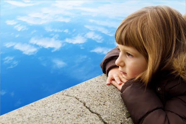Menina olhando para o mar, enquanto apoiado na parede — Fotografia de Stock