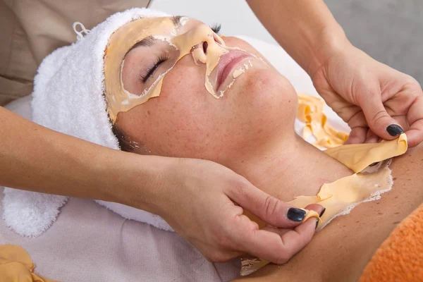 Hermosa joven mujer quitar la máscara facial en un centro de belleza — Foto de Stock