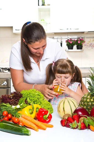 Schöne junge Frau gibt dem kleinen Mädchen Orangensaft in — Stockfoto