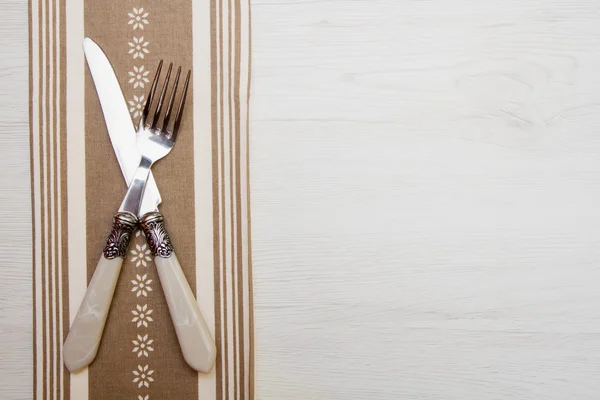 knife and fork at napkin on white wooden background