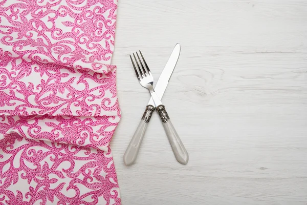 Couteau et fourchette à serviette sur fond blanc en bois — Photo