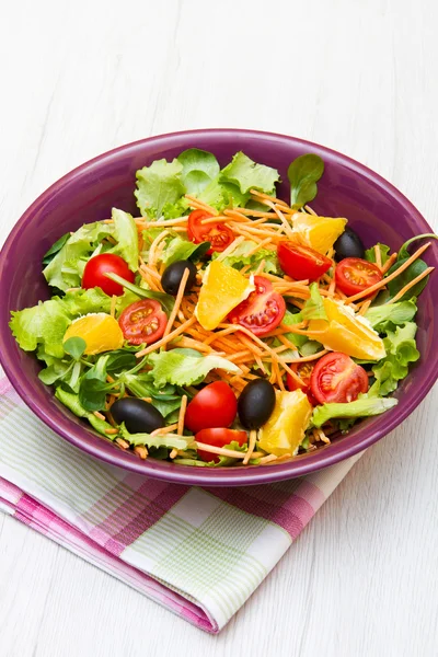 Ensalada mixta con tomates en tazón púrpura sobre mesa de madera —  Fotos de Stock