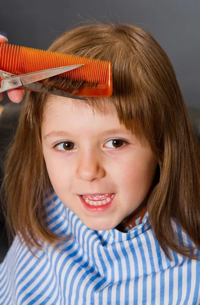 Frisör gör en frisyr till söt liten flicka — Stockfoto