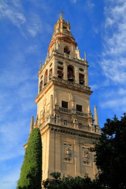 Cordoba 'nın Mezquita-Katedrali' nin antik çan kulesi canlı mavi gökyüzüne karşı yükselir, yıpranmış taşlar, kemerli çan odaları ve geleneksel bronz çanlar sergilenir..