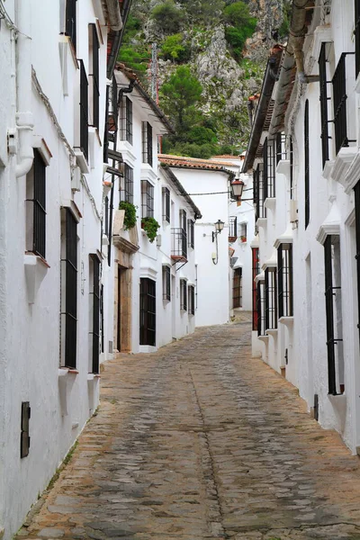 Tarihsel beyazlatılmış atari salonu bir çan kulesi ve parlak mavi gökyüzünün altındaki demir kapıyla süslü taş bir kapı çerçevesi, Vejer de la Frontera, İspanya