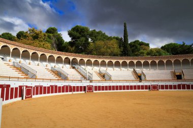 Boş bir İspanyol boğa güreşi arenası kemerli galerilerini, katlı koltuklarını ve kumlu çukurunu sergiliyor. Toros de Antequera Meydanı