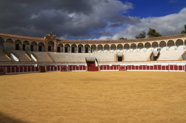 Boş bir İspanyol boğa güreşi arenası kemerli galerilerini, katlı koltuklarını ve kumlu çukurunu sergiliyor. Toros de Antequera Meydanı