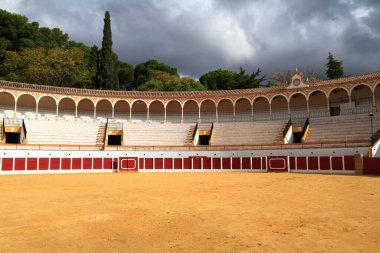 Boş bir İspanyol boğa güreşi arenası kemerli galerilerini, katlı koltuklarını ve kumlu çukurunu sergiliyor. Toros de Antequera Meydanı