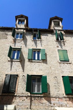 Güneşli bir günde pek çok pencere ve balkona sahip tarihi taş binalar, klasik Avrupa mimarisinin sergilendiği dar bir cadde..