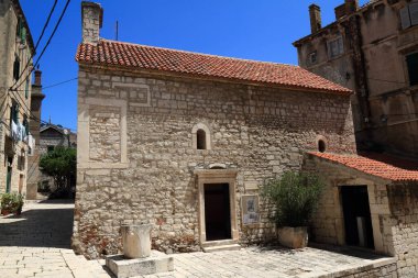 Güneşli bir günde pek çok pencere ve balkona sahip tarihi taş binalar, klasik Avrupa mimarisinin sergilendiği dar bir cadde..