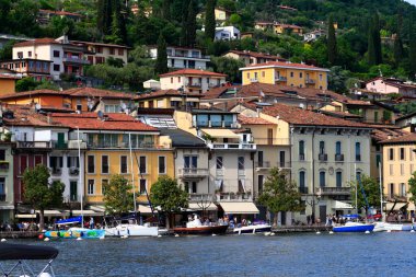 İtalya 'nın Garda Gölü' ndeki büyüleyici göl köyünün manzarasında renkli binalar, tekneler ve yemyeşil alanlar yer alıyor. Seyahat, turizm ve yaşam tarzı pazarlama için ideal.