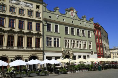 Karmaşık cepheli tarihi Avrupa binaları büyüleyici bir cadde çiziyor. Beyaz şemsiyeli açık hava kafeler ziyaretçileri güneşli günün ve hareketli atmosferin tadını çıkarmaya davet ediyor..