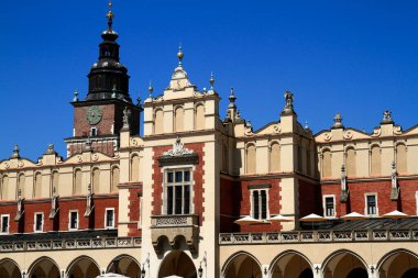 Belirgin bir saat kulesinin ve parlak mavi gökyüzüne karşı karmaşık mimari detayların yer aldığı süslü bir tarihi binanın görüntüsü.