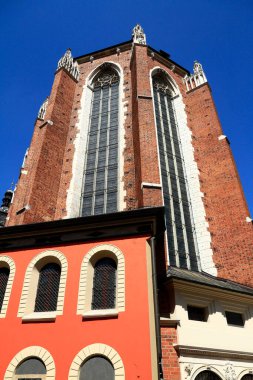 Avrupa 'nın tarihi bir kilise binasının çarpıcı bir görüntüsü, uzun tuğlalı cephesi, kemerli pencereleri ve karmaşık mimari detayları, canlı mavi gökyüzüne karşı kurulmuş..
