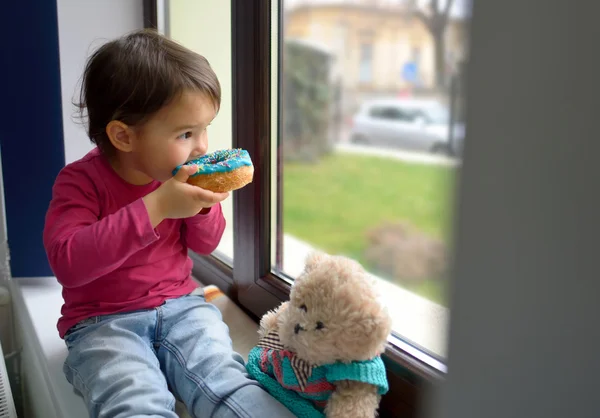 Kleines Mädchen isst Donuts Stockfoto