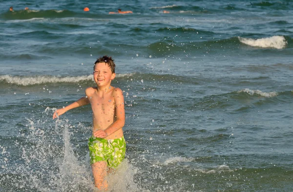 Garçon courir à travers les vagues — Photo