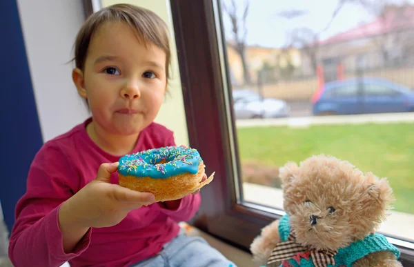 Little girl eating donuts — Stock Photo, Image