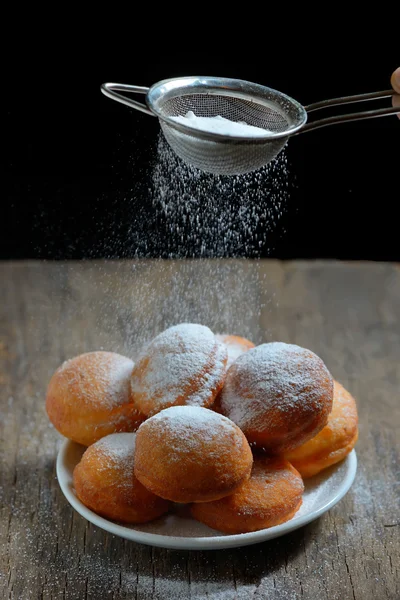 Sugar with strainer over donuts — Stock Photo, Image