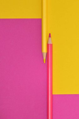 Abstract yellow and pink crayons on the same paper background