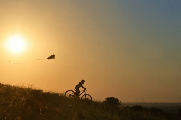Silhouette Νεαρό Αγόρι Παίζει Kite Ιππασία Του Στο Ποδήλατο — Φωτογραφία Αρχείου