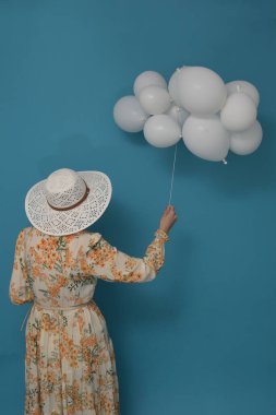 Bulutlu bir gün. Mavi gökyüzüne karşı kadın ve beyaz balonlarla kavram