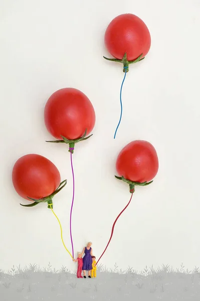 小家庭与红色樱桃番茄中的气球玩耍 — 图库照片