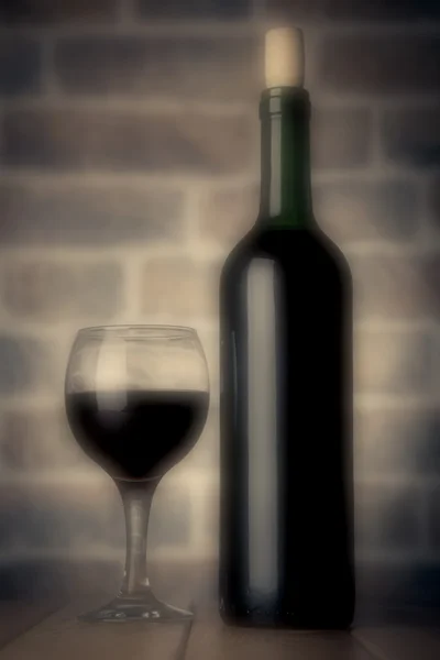 Красная бутылка вина и бокал на деревянном столе цвета фильтры размыты — стоковое фото