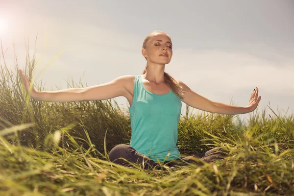 Sarışın genç kadın gözleri kapalı doğa üzerinde meditasyon — Stok fotoğraf