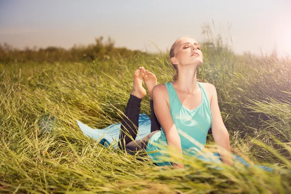 Giovane bionda bella donna che fa esercizi di yoga sull'erba — Foto Stock