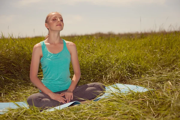 Sarışın genç kadın gözleri kapalı doğa üzerinde meditasyon — Stok fotoğraf