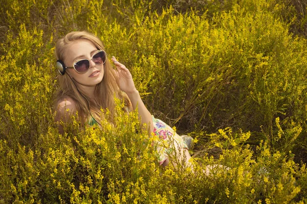 Blond kobieta z słuchawkami na zewnątrz pola, słuchanie muzyki — Zdjęcie stockowe