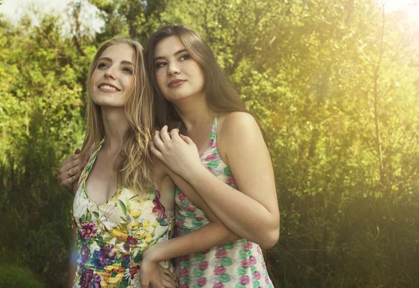 Twee mooie meisjes een omhelzing blijven over de aard — Stockfoto