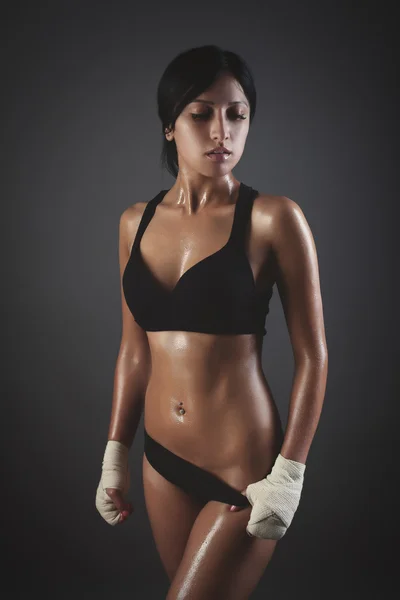 Жінка в спортивному одязі розслабляється після тренування на сірому фоні — стокове фото