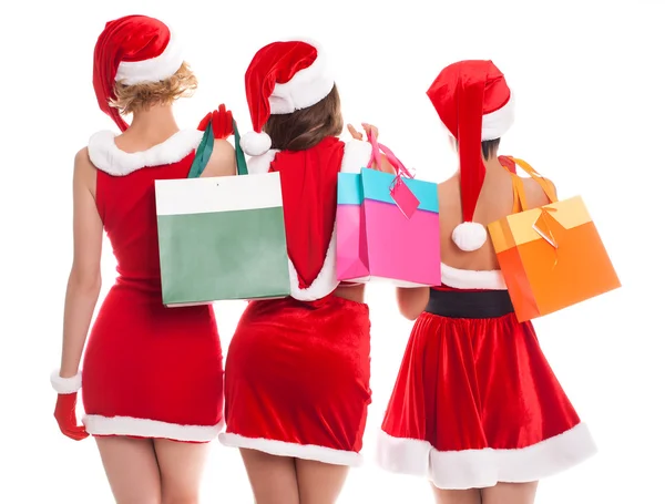 Three happy shopping girls holding bags and wearing Christmas ha — Stock Photo, Image