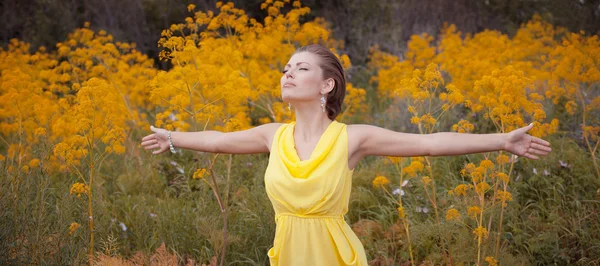 Jonge vrouw in gele jurk in natuur positieve portret — Stockfoto