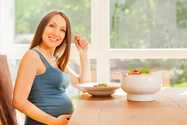 Mujer embarazada está comiendo gran porción de pasta con salsa de tomate — Foto de Stock