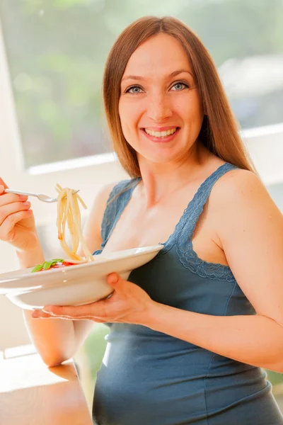 Mulher grávida está comendo grande porção de massa com molho de tomate — Fotografia de Stock