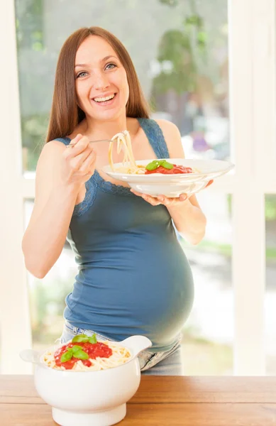 Mujer embarazada está comiendo gran porción de pasta con salsa de tomate —  Fotos de Stock