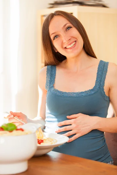 Těhotná žena se jí obrovské porce těstovin s rajčatovou omáčkou — Stock fotografie