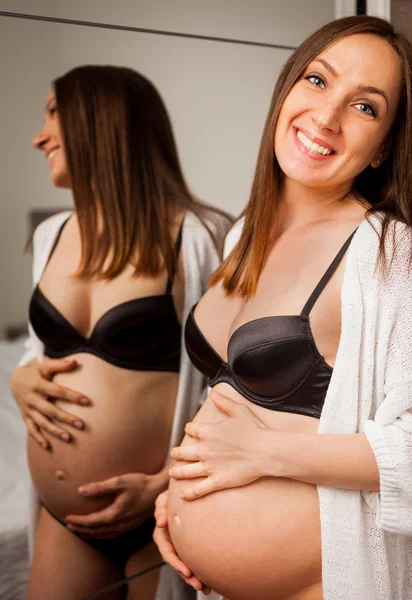Attraktive Schwangere in Dessous posiert vor ihrem Bett — Stockfoto