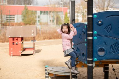 Küçük kız oyun bahçesinde oynuyor.