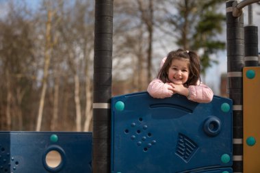 Küçük kız oyun bahçesinde oynuyor.