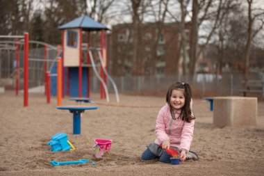 Küçük kız oyun bahçesinde oynuyor.