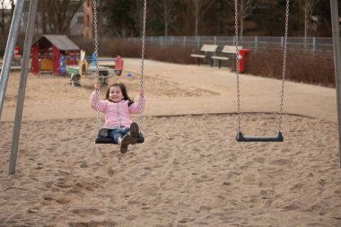 Küçük kız oyun bahçesinde oynuyor.