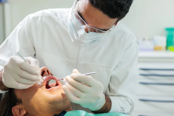 Dentista está fazendo um check-up em um homem de 40 anos de idade — Fotografia de Stock