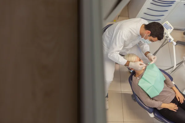 Draufsicht des kaukasischen Zahnarztes, der seine Arbeit an einer jungen Blondine verrichtet — Stockfoto