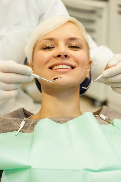 Loira sorrindo mulher sentada no dentista e olhando para — Fotografia de Stock