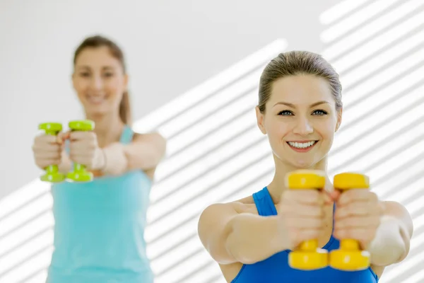 İki genç çekici kadın içinde dumbbells ile egzersizleri yapıyor — Stok fotoğraf