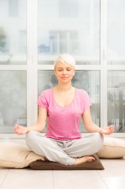 sarışın kadının evde meditasyon yapması